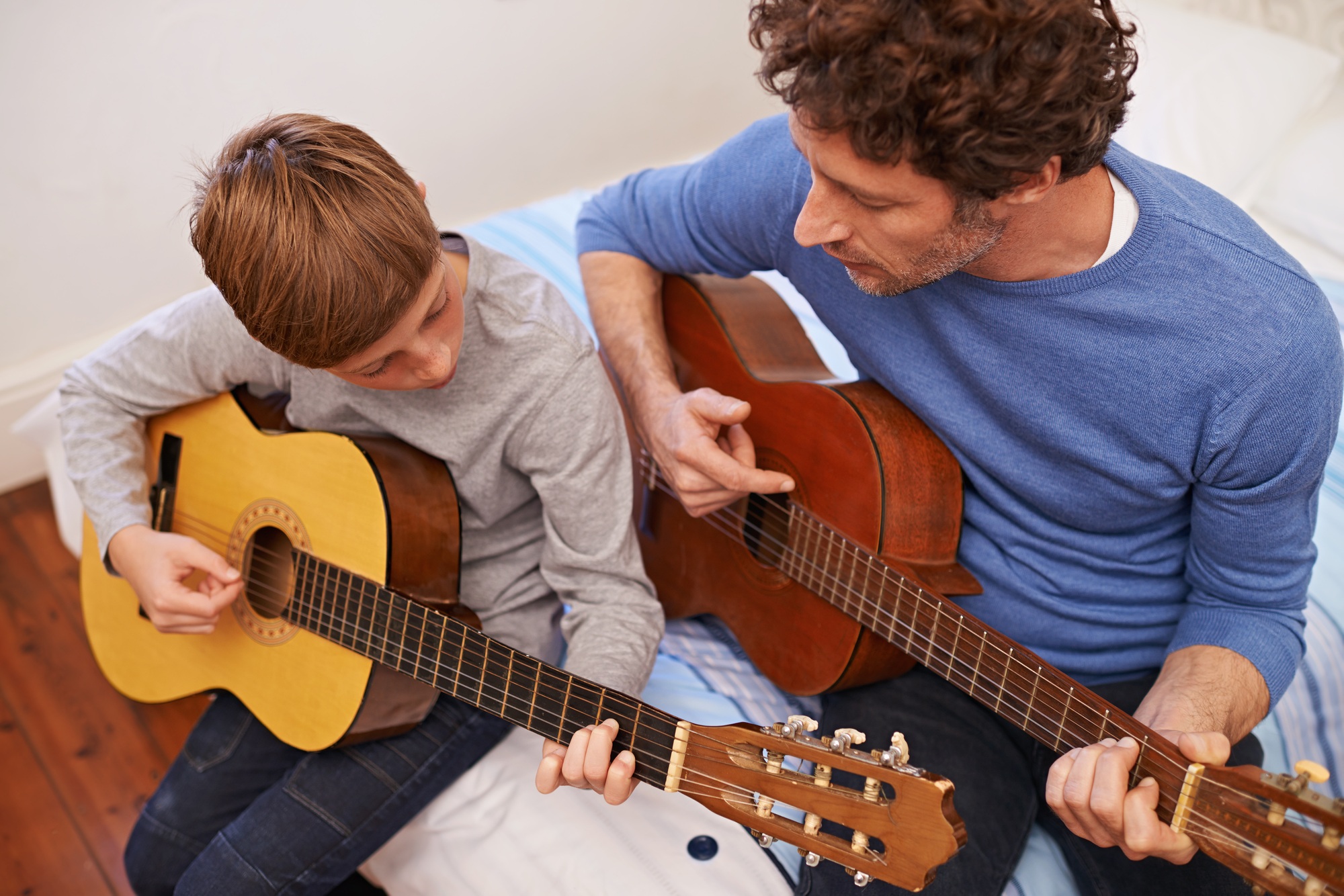 Getting it right together. Shot of a father teaching his son the guitar.