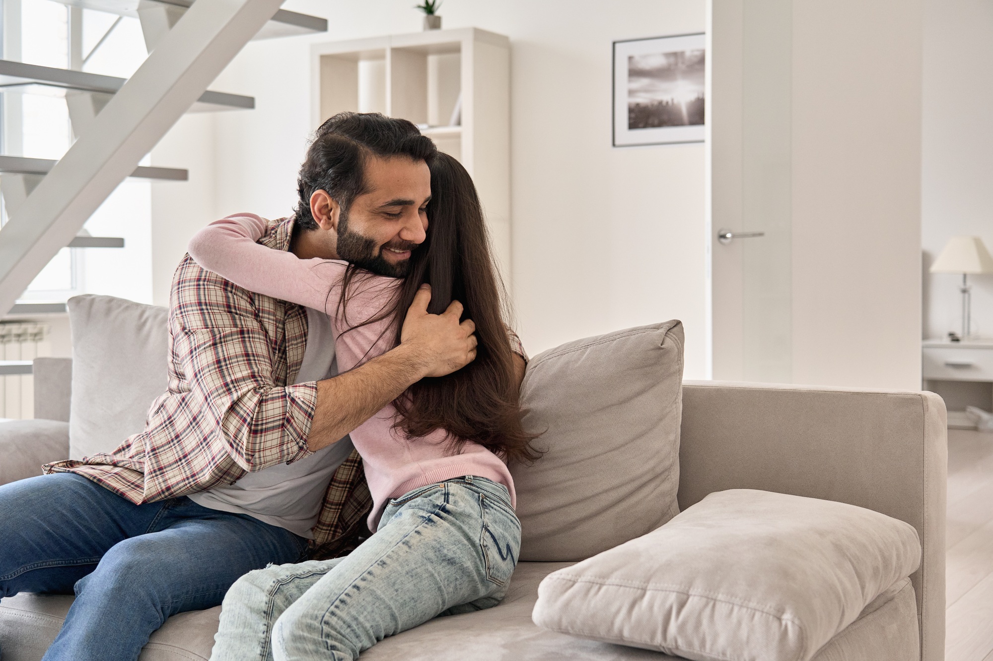 Happy indian teen child daughter embracing dad at home on fathers day.