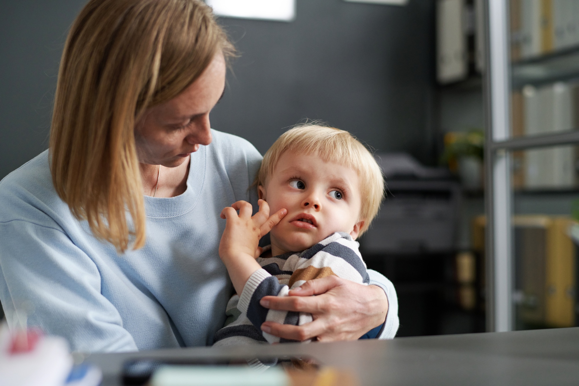 Young woman with little son sitting in office